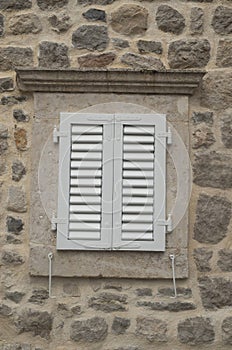 Traditional new white window shutters as blinds on old stone home