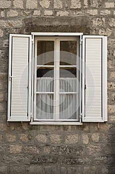 Traditional new white window shutters as blinds on old stone home