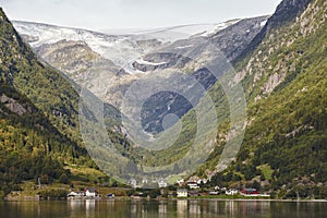 Traditional norwegian fjord village with glacier. Hardanger rout