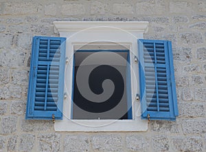 Traditional old blue window shutters as blinds on old stone home