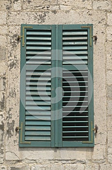 Traditional old green window shutters as blinds on old stone home