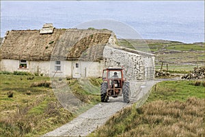 Traditional old irish house with a male on a tractor