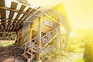 Traditional old wooden house in sunlight. Stairway from cartwheels with standing bicycles