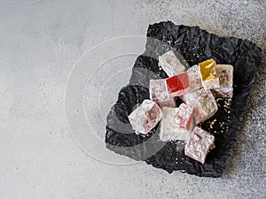 Traditional oriental dessert Turkish Delight on black paper on grey background. Copy space