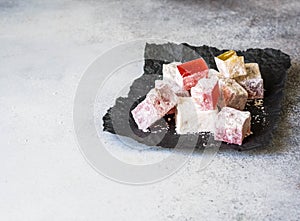 Traditional oriental dessert Turkish Delight on black paper on grey background. Copy space