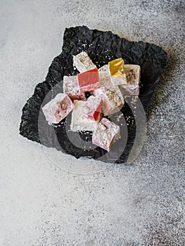 Traditional oriental dessert Turkish Delight on black paper on grey background. Copy space