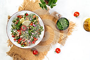 Traditional oriental salad Tabouleh with bulgur and parsley on a light background, top view