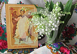 Traditional orthodox icon of the Holy Guardian Angel. Handwritten work background of Ukrainian rushnyks and lilies of