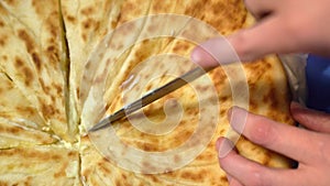 Traditional Ossetian pie. Cutting with a knife.