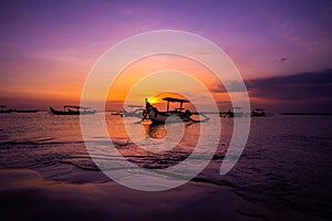 Traditional outrigger fishing boats silhouetted against a sunset, Bali Indonesia