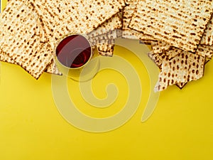 Traditional Passover Jewish kosher bread matzah and a glass of red wine on a bright yellow background. A festive treat for Jewish