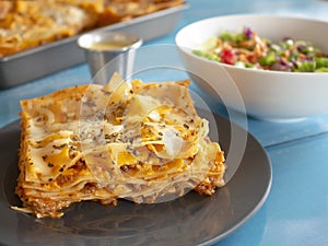 Traditional Pasta Plate of Lasagna with Basil Tomato Sauce Cream White Cheese and Ground Beef and Salad