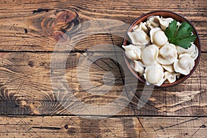 Traditional pelmeni, ravioli, dumplings filled with meat on plate, russian kitchen. Wooden rustic background, copy space