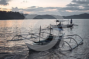 Traditional Philippino fishermen returning home on their boats to a bay during sunset in El Nido Palawan the Philippines