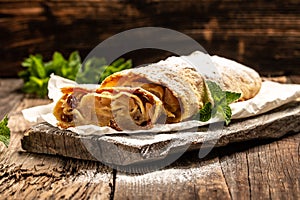 Traditional piece of apple strudel with powdered sugar and mint closeup on a wooden background. copy space