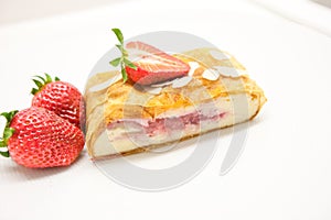 Traditional piece of strawberry strudel with powdered sugar closeup on a table.