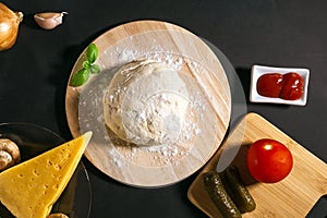 Traditional pizza ingredients: cheese, tomatoes, sauce, olive oil, spices, mushrooms. Black texture background. the view from the