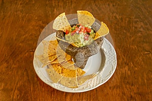 Traditional plate of Mexican guacamole with corn chips and pico de gallo