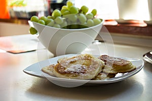 Traditional Polish pancakes on a white plate and green grapes on a kitchen counter