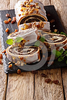 Traditional Polish poppy roll with raisins, walnuts and mint close-up on a table. vertical