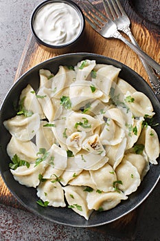 Traditional Polish ravioli dumplings or uszka served with sour cream closeup on the plate on the table. Vertical top view