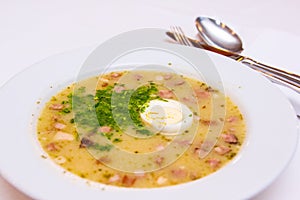 Traditional polish white borscht - zurek, sour soup with white sausages and eggs