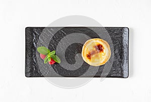 Traditional Portugal food - dessert egg custard tart pastry, consisting of egg yolk, dough and cinnamon on a black serving board