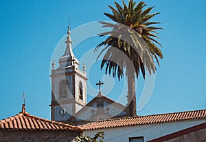 Traditional portuguese church with azulejos tiles with palm tree and old buildings. Mediterranean religious landmark.