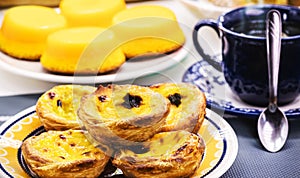 Traditional Portuguese dessert of pastel de nata, and bree de lis in the background, served with coffee, typical sweet made with