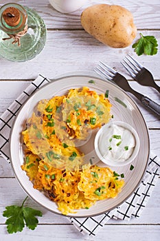 Traditional potato latkes with greens and sauce on a plate on the table top and vertical view