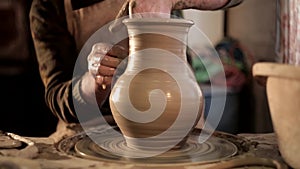 Traditional pottery making, close up of potter`s hands shaping a bowl on the spinning by clay