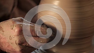 Traditional pottery making, close up of potter`s hands shaping a bowl on the spinning by clay