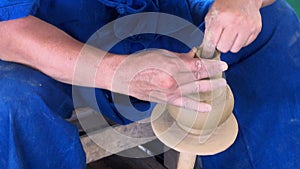 Traditional pottery making, close-up of potter`s hands shaping a vase on the spinning by clay