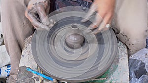 Traditional pottery making, close-up of potter`s hands shaping a vase on the spinning by clay