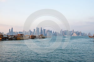 Traditional Qatari dhow boats with the skyline of Doha West Bay skyscrapers