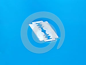 A traditional razor blade lies on the water, close-up