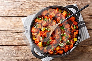 Traditional recipe for chili sweet potatoes and black beans with tomatoes, celery close-up in a pan. Horizontal top view