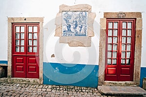 Traditonal red doors with white walls and blue accents in Obidos Portugal