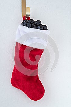 Traditional red and white plush Christmas stocking stuffed with coal shaped candy