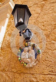 Traditional religious catholic bas-relief od Virgin Mary with baby Jesus near the building entrance in Mdina, Malta