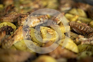 Traditional roast potatoes and chicken wings in the oven seasoned with rosemary