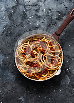 Traditional Roman pasta - bucatini amatricana in a pan on a dark background, top view