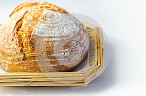 Traditional round loaf of bread baked according to a classic recipe, served on a wicker basket