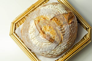 Traditional round loaf of bread baked according to a classic recipe, served on a wicker tray