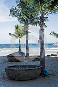 Traditional round Vietnamese boats and palm trees on Danang beach