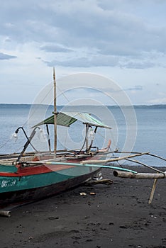 Traditional rowboat on a volcanic beach at Tabaco in the Philippines photo