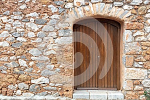 Traditional rural home facade background. Stonewall cottage exterior with wooden brown door. Greece