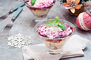 Traditional Russian appetizer of boiled vegetables and fish - a herring under a fur coat in bowls in Christmas decorations