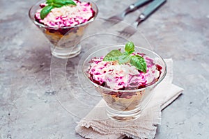 Traditional Russian appetizer of boiled vegetables and fish - a herring under a fur coat in bowls on the table