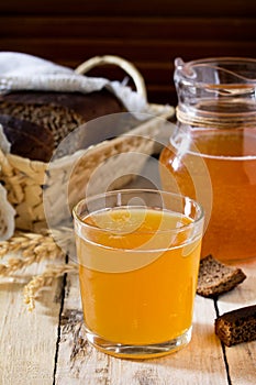 Traditional Russian cold rye drink Kvas in a glass and a jug on the kitchen table in a rustic style.